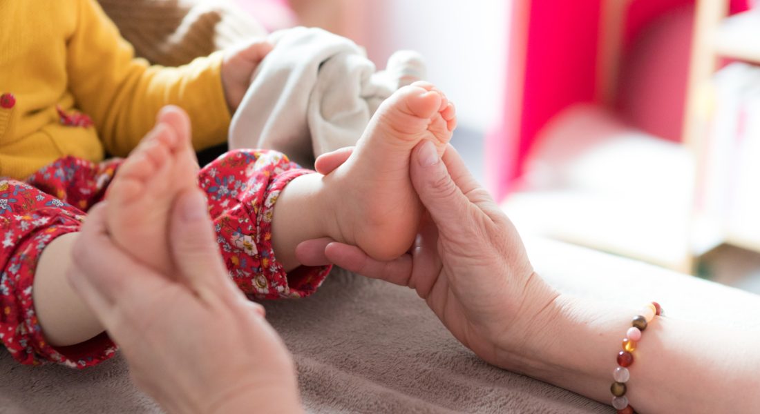 Muriel Le Négaret qui pratique une séance de réflexologie plantaire avec un petit enfant